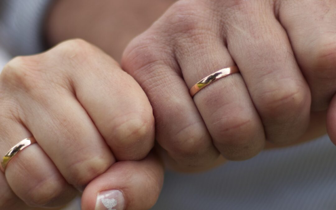 a couple wearing wedding rings on their right hands